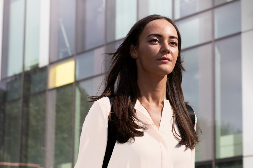 Image of a women walking with an office building in background