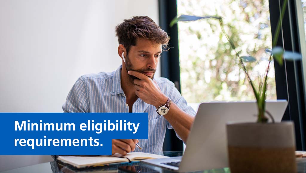 Image of a men working on a computer at a desk.  Text reads "minimum eligibility requirements"