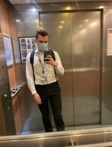 Image of a person taking a selfie in a lift. They are wearing a face mask.